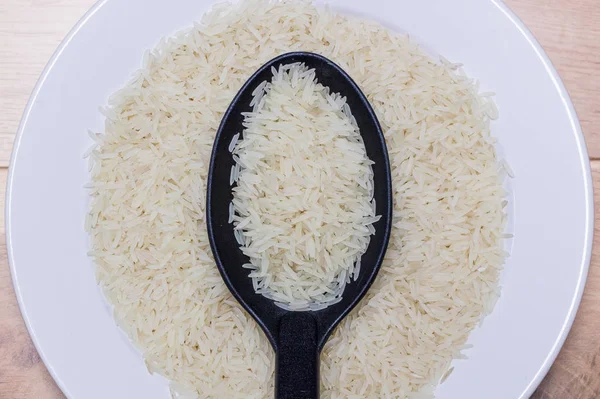 Siyah kaşık beyaz tabakta basmati pirinç dolu. Üstten görünüm