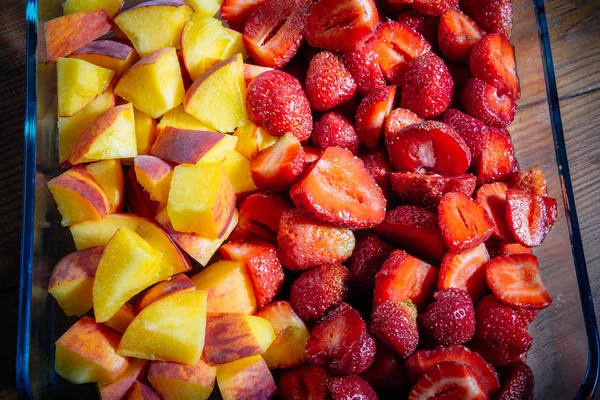 Şeftali ve çilek ahşap bir masa üzerinde bir cam levha içinde parçaları