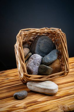 gri bir arka plan üzerinde ahşap bir masa üzerinde bir sepet içinde taşlar