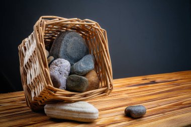 gri bir arka plan üzerinde ahşap bir masa üzerinde bir sepet içinde taşlar