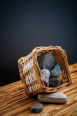 gri bir arka plan üzerinde ahşap bir masa üzerinde bir sepet içinde taşlar