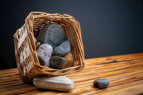 gri bir arka plan üzerinde ahşap bir masa üzerinde bir sepet içinde taşlar