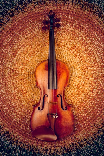 An old violin on a colored knitted rug of warm tones