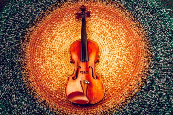 An old violin on a colored knitted rug of warm tones