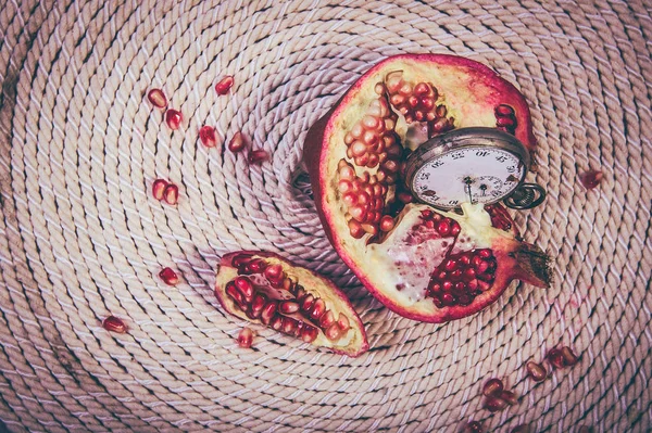 an ancient stopwatch and a pomegranate on the background of a spiral rope