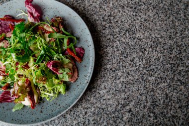 Biftek salata, parmesan peyniri, gri bir tabak içinde.
