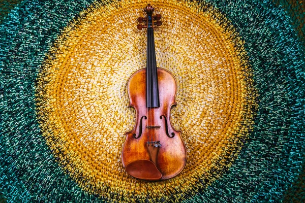 An old violin on a colored knitted rug of warm tones