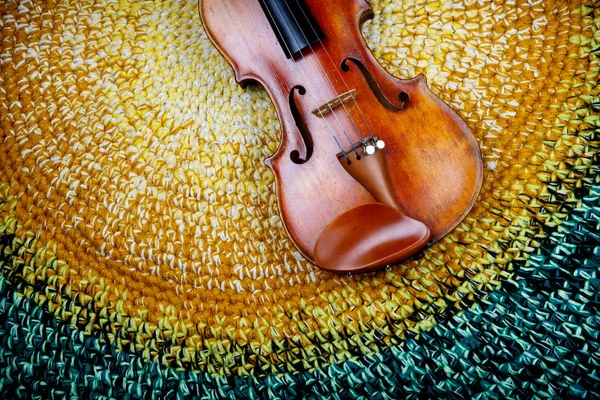 An old violin on a colored knitted rug of warm tones