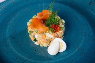 Somon ve yumurta ile mavi tabakta Rus salatası