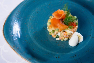 Somon ve yumurta ile mavi tabakta Rus salatası