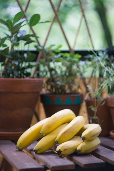 Ett gäng mogna gula bananer på ett träbord på en terrass — Stockfoto