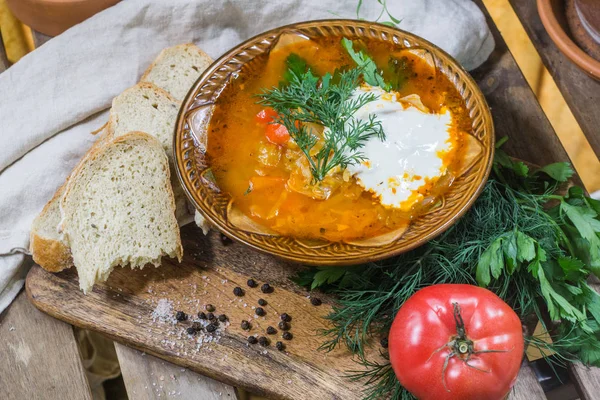 Traditionelle russische Sauerkrautsuppe shchi mit saurer Sahne und Kräutern auf einem Holztisch mit Brot, Pfeffer und Petersilie — Stockfoto