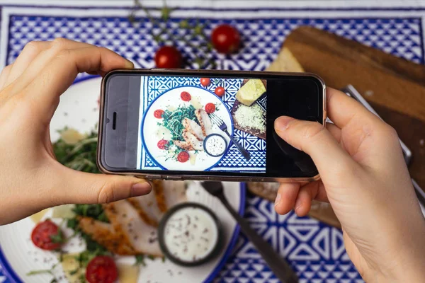 Food photography: the girl is taking a photo of Caesar salad. Food photo for social networks — Stock Photo, Image