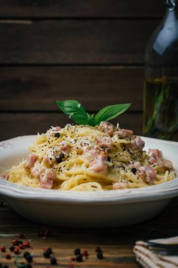 Spagetti Carbonara. Makarna alla carbonara bir krema sos, pastırma ve beyaz tabakta biber ile. Eski ahşap arka plan. Kopya alanı.