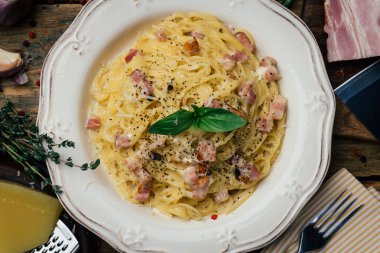 Spagetti Carbonara. Makarna alla carbonara bir krema sos, pastırma ve beyaz tabakta biber ile. Eski ahşap arka plan