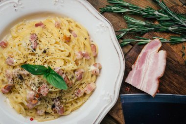 Spagetti Carbonara. Makarna alla carbonara bir krema sos, pastırma ve beyaz tabakta biber ile. Eski ahşap arka plan