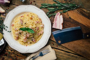 Spagetti Carbonara. Makarna alla carbonara bir krema sos, pastırma ve beyaz tabakta biber ile. Eski ahşap arka plan
