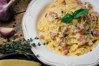 Spagetti Carbonara. Makarna alla carbonara bir krema sos, pastırma ve beyaz tabakta biber ile. Eski ahşap arka plan
