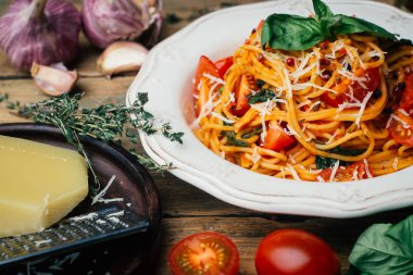 Spagetti makarna domates sos, parmesan ve fesleğen beyaz tabakta. Klasik domates spagetti: Vejetaryen domates fesleğen makarna. Eski ahşap arka plan