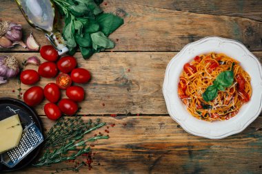 Spagetti makarna domates sos, parmesan ve fesleğen beyaz tabakta. Klasik domates spagetti: Vejetaryen domates fesleğen makarna. Eski ahşap arka plan. Kopya alanı.