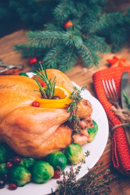 Bütün Noel tavuk ile garnitür, portakal, biberiye ve kekik bir ahşap zemin üzerine pişmiş. Rustik tablo ayarı. Noel yemeği.