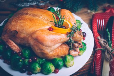 Bütün Noel tavuk ile garnitür, portakal, biberiye ve kekik bir ahşap zemin üzerine pişmiş. Rustik tablo ayarı. Noel yemeği.