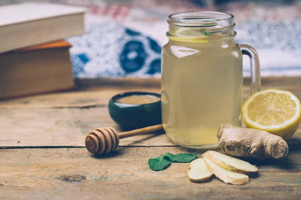 Hot drink with honey, lemon and ginger on wooden background. Concept of natural medicine. Winter or autumn drinks.