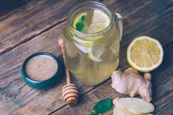 Hot drink with honey, lemon and ginger on wooden background. Concept of natural medicine. Winter or autumn drinks.