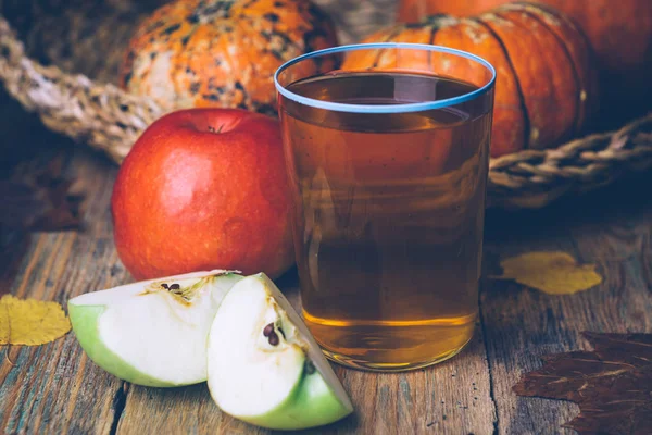 Cold apple cider or apple juice with fresh apples on a wooden background. Autumn drinks. Autumn mood.