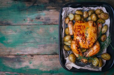 Kekik ile kavrulmuş tavuk patates, portakal ve baharat ahşap masa üzerinde siyah pişirme çanağı yılları arasında görev yapmıştır. Şükran veya Noel akşam yemeği. Üstten görünüm