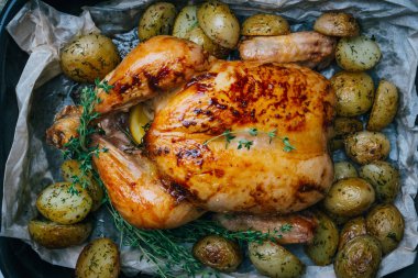 Kekik ile kavrulmuş tavuk patates, portakal ve baharat ahşap masa üzerinde siyah pişirme çanağı yılları arasında görev yapmıştır. Şükran veya Noel akşam yemeği. Üstten görünüm