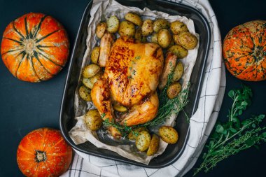 Kekik ile kavrulmuş tavuk patates, portakal ve baharat ahşap masa üzerinde siyah pişirme çanağı yılları arasında görev yapmıştır. Şükran veya Noel akşam yemeği. Üstten görünüm