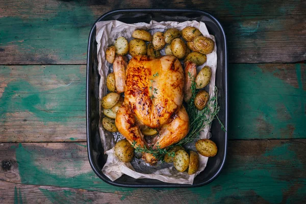 Kekik ile kavrulmuş tavuk patates, portakal ve baharat ahşap masa üzerinde siyah pişirme çanağı yılları arasında görev yapmıştır. Şükran veya Noel akşam yemeği. Üstten görünüm