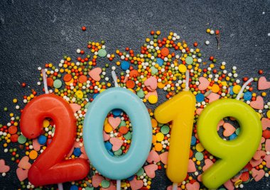 2019 Yılbaşı mumlar renkli festival şeker ile karanlık bir arka plan üzerinde. Yeni yıl partisi konsepti. Kopya alanı.