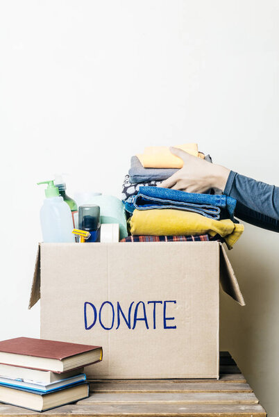 Одевает донацию и кормовую донацию. Женщина с коробкой для пожертвований с одеждой, обувью и средствами гигиены
.