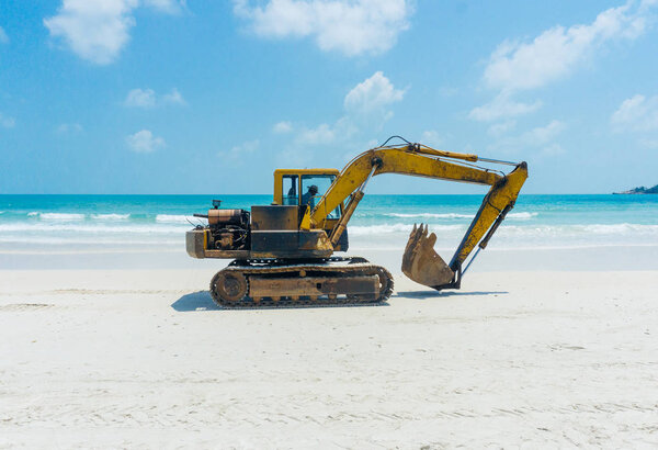 Excavator (digger, dredger, dredge) on the sunny sea beach. Asia.