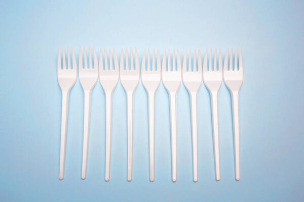 Single-use plastic products: plastic cutlery, cups on bright blu