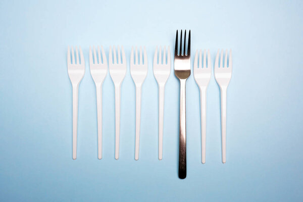 Plastic and metal fork on bright blue background. Creative minim
