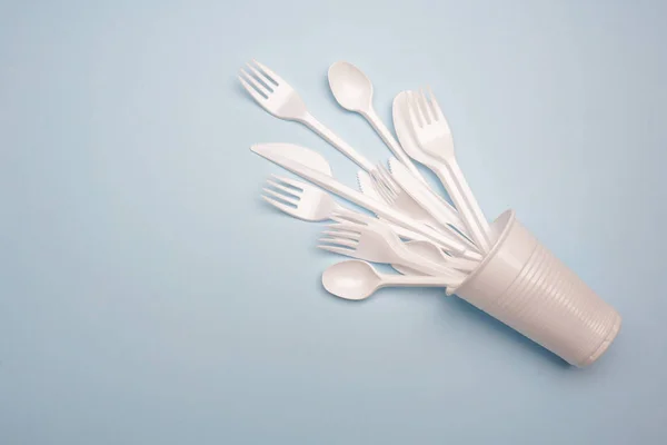 Single-use plastic products: plastic cutlery, cups on bright blu — Stock Photo, Image