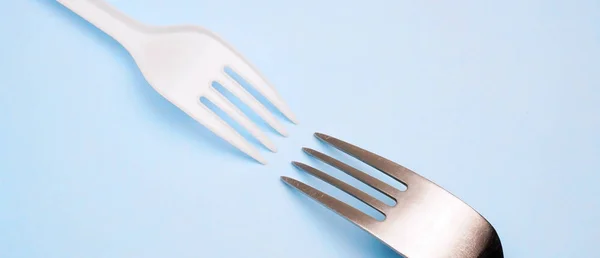 Plastic and metal fork on blue background. Minimal concept — Stock Photo, Image