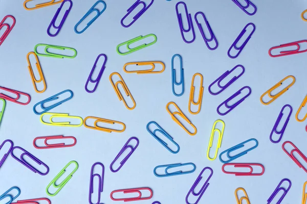 Color clips minimal concept. Colored paper clips on a colored ba