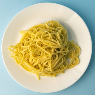 Mavi arka planda beyaz tabakta makarna. Yaratıcı,