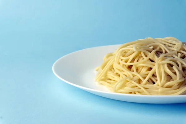 Spaghetti pasta på en vit platta på en blå bakgrund. Kreativ, — Stockfoto
