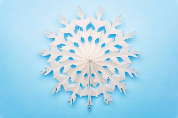 Bílá sněhová vločka (nebo slunce) z papíru na modrém pozadí. Chr — Stock fotografie
