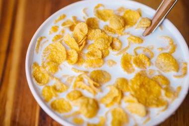 Tahta mutfak masasında sütlü kahvaltı gevreği. Sağlıklı kahvaltı geçmişi