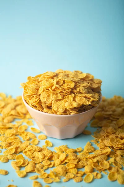 Cereal (cornflakes) for breakfast in a pink bowl on a blue background. Minamal art creative food concept