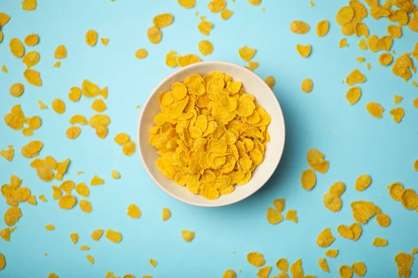 Cereal (cornflakes) for breakfast in a pink bowl on a blue background. Minamal art creative food concept