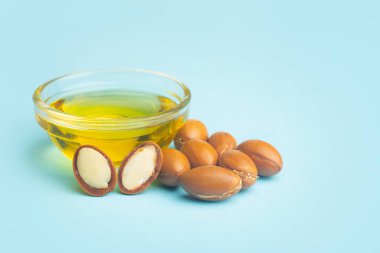 Koyu mavi bir arka planda Argan tohumları ve yağı. Argan yağı bazlı kozmetik konsepti.