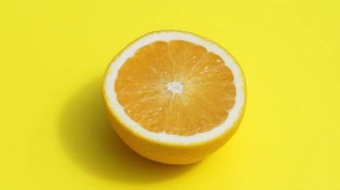 Sarı arka planda turuncu dönen izole edilmiş. Renkli pastel arka planda yaz güneşinde sulu taze sarı portakal. Taze meyve suyu, meyve, vitamin ve yaz konsepti.