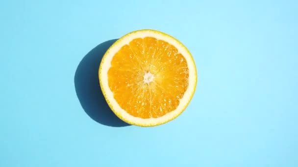 青の背景にオレンジを回転させると隔離されます 夏の日差しの中で新鮮な黄色のオレンジを色のパステルカラーの背景でジューシーに フレッシュジュース フルーツ ビタミン 夏のコンセプト — ストック動画